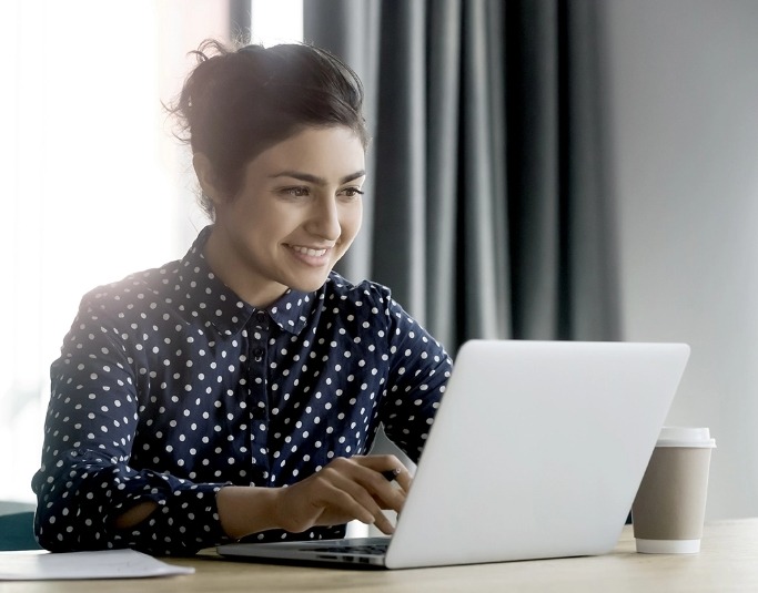 woman smiling at laptop on desk image