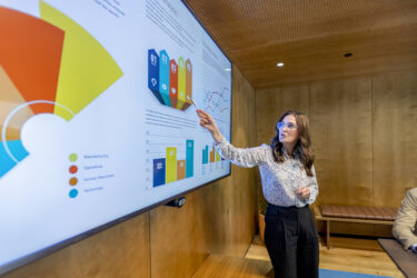 Woman giving a big data presentation on a tv in a board room.
