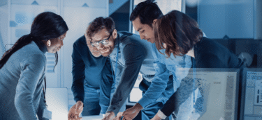 group of people standing around a desk collaborating image