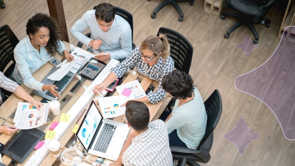 Group of people crowded around a desk having a discussion