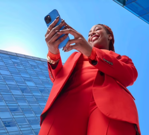 smiling black woman holding smartphone dressed in red suit