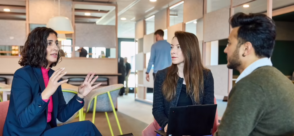 Woman speaking with two other people on chairs in office header image